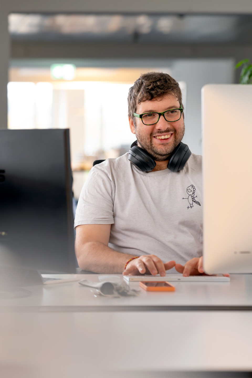 Benedikt Grether lächelnd am Schreibtisch vor seinem Rechner